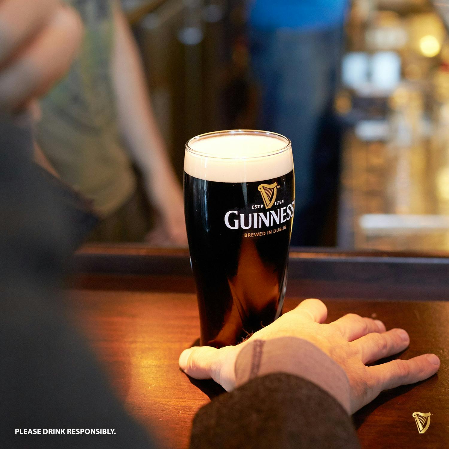 man sat up at the bar with pint of Guinness