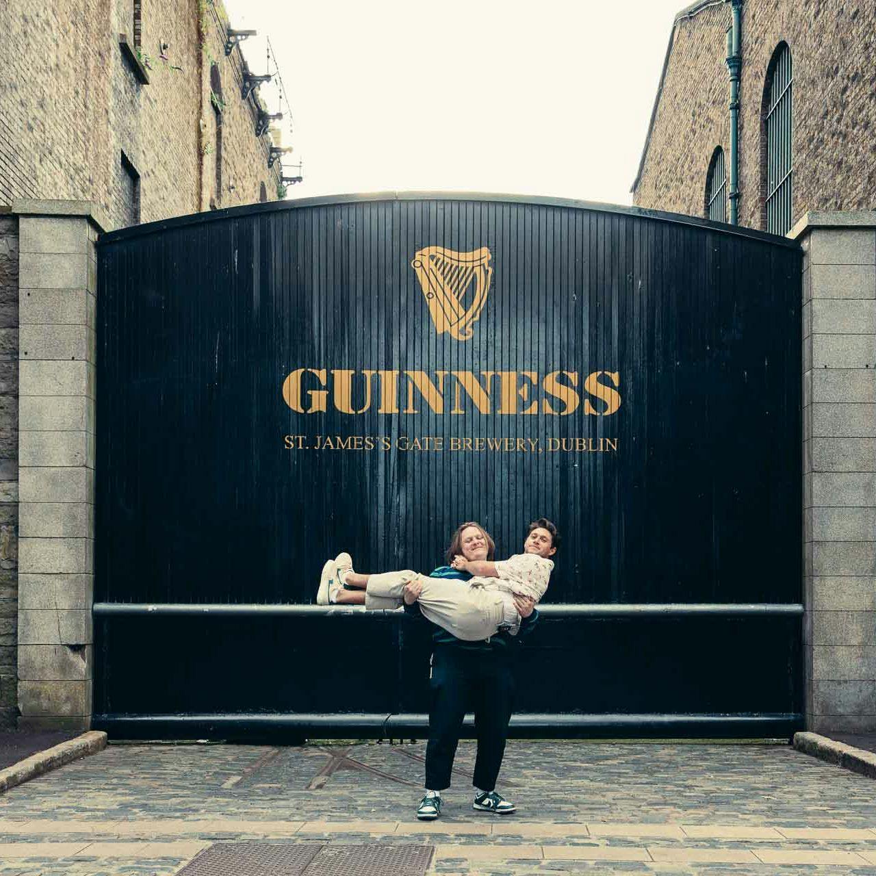 a woman is holding a man at the front gate of guinness