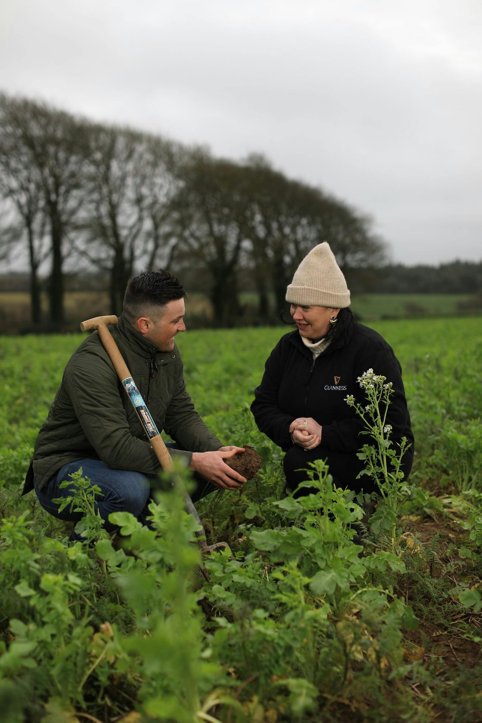 Image of two farmers inspecting the soil in a field