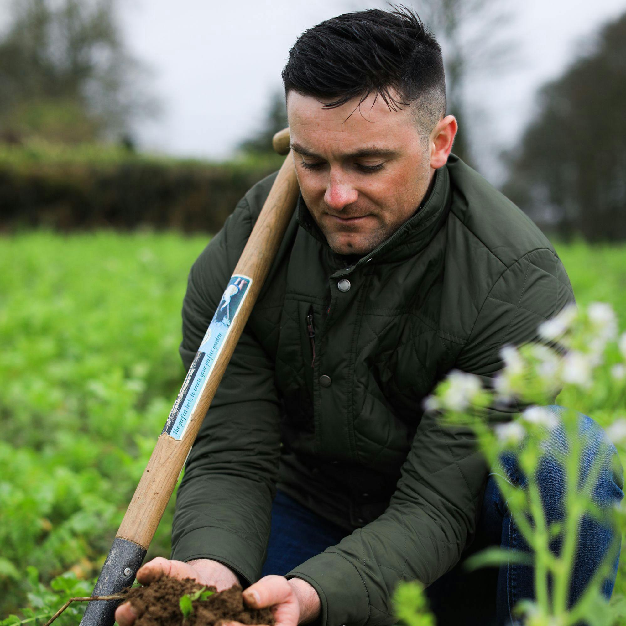 Walter Furlong Junior of the Guinness regenerative agriculture programme picking up a soil sample
