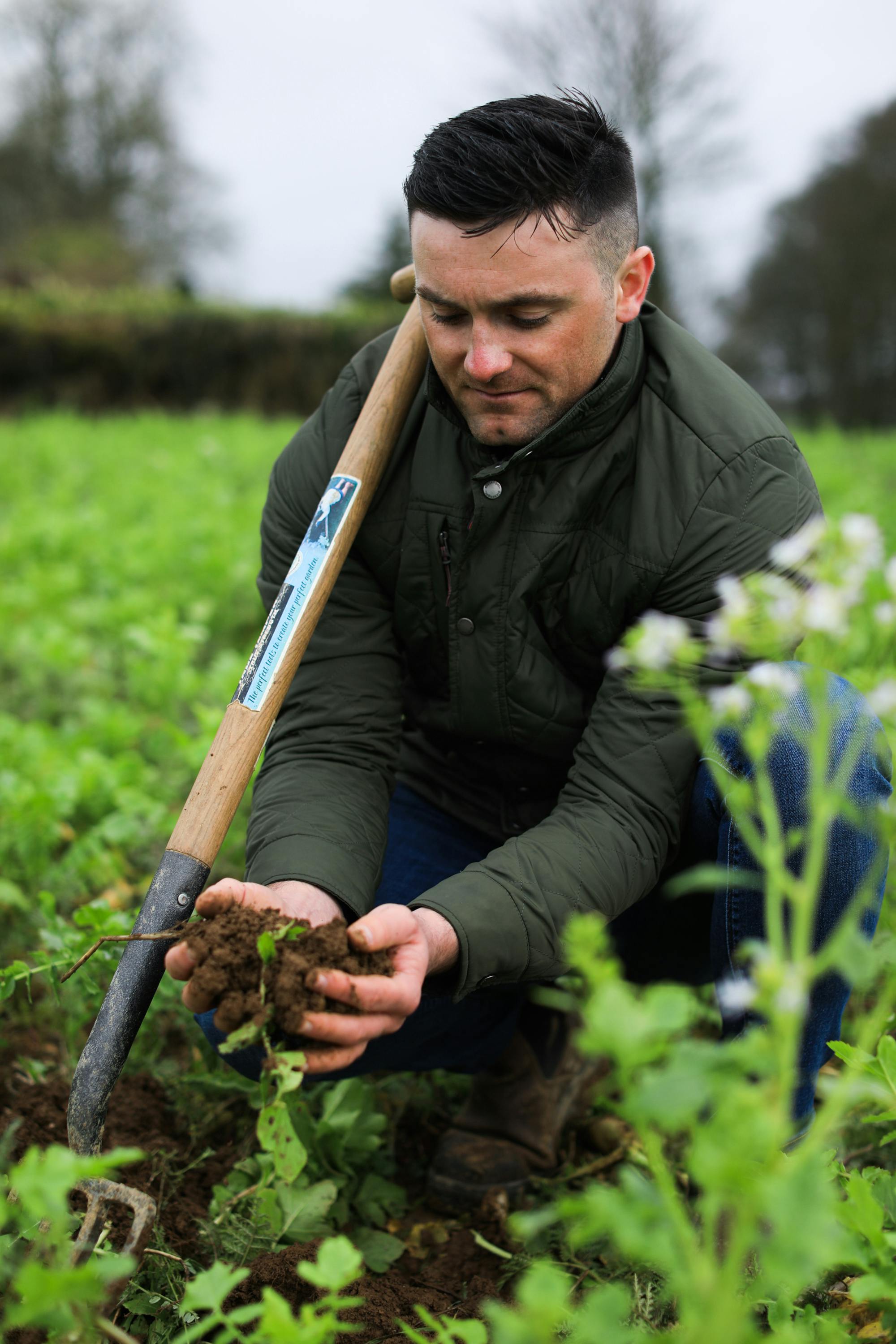 Walter Furlong Junior of the Guinness regenerative agriculture programme picking up a soil sample